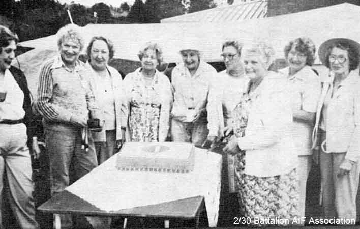 Makan 265
"Display of cake baked by Georgina Geoghegan with Battalion Colour Patch before being cut as above."

Left to right:
1) Grace Ford
2) Gretta Maston
3) Thema Jones
4) Heather McClelland
5) Norma Christensen
6) Pat Nossiter
7) Georgina Geoghegan
8) Madge Napper
9) Joan Crispin
Keywords: Makan265