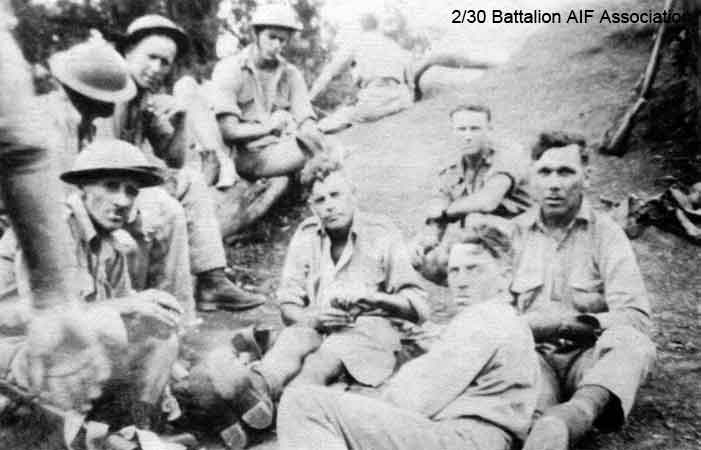 B Company, 12 Platoon, 8 Section
Training at Bathurst.

Left to right:

Sitting on log:
1) NX26000 - EVANS, Frederick John (Tommy), Pte. - B Company, 12 Platoon (looking at camera)
2) NX26332 - SYLVESTER, Walter Hackshall (Tiger), Pte. - B Company, 12 Platoon (helmet hides face)
3) NX32129 - HODGES, Alfred Edward (Fred or Snowy), Pte. - B Company, 12 Platoon
4) NX59100 - GILBERT, Allen John, L/Cpl. - B Company, 12 Platoon

Lying in front:
1) NX29655 - GILL, Edward George Laurence (Blondie or Ted), Pte. - B Company, 12 Platoon

Sitting on ground:
1) NX26933 - PICKARD, D'Arcy Stanley, Pte. - B Company, 12 Platoon
2) NX26330 (NX5078) - CHARLTON, Ronald Alan (Zipper or Ron), Pte. - B Company, 12 Platoon
3) NX29656 - RUSSELL, Harold Edward, Cpl. - B Company, 12 Platoon

In background, back to camera:
1) NX26331 - HOLLAND, Bruce Hedley (Dutchy), Pte. - B Company, 12 Platoon
Keywords: 061222 Makan269