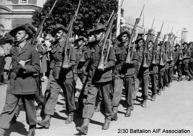 Signals Platoon, Tamworth
Signals Platoon marching in Tamworth, February, 1941.

Leading the Platoon:
1) NX70448 - FARR, Albert Irwin (Bub or Bert), Lt. - HQ Company, O/C Signals Platoon

Behind leader (left to right - visible men only):
2) NX45174 - LONIE, John Graham (Jack), Pte. - HQ Company, Signals Platoon (middle of 1st row behind leader)
3) NX55172 - PHILLIPS, Clarence James (Tankie), Pte. - HQ Company, Signals Platoon (far side of 3rd row behind leader)
4) NX25715 - MASSEY, Thomas Fox (Hank), L/Cpl. - HQ Company, Signals Platoon (middle of 2nd row behind leader)
5) NX47129 - COOTE, George Bentley, Pte. - HQ Company, Signals Platoon (near side of 1st row behind leader)
6) NX65486 - QUINTAL, Laurie Patterson, Pte. - HQ Company, Signals Platoon (near side of 2nd row behind leader)
7) NX54980 - BARTLETT, Andrew John (Jack), Pte. - HQ Company, Signals Platoon (near side of 3rd row behind leader - with glasses)
8) NX32505 - STARR, Walter Edwin (Wally), Pte. - HQ Company, Signals Platoon (near side of 4th row behind leader)
9) NX46196 - DAVISON, Robert Shaw (Scotty), Pte. - HQ Company, Signals Platoon (near side of 5th row behind leader)
10) NX2719 - COTTER, Percy Augustine, Pte. - HQ Company, Signals Platoon (near side of 8th row behind leader - turning corner)
11) NX37499 - LUSBY, Robert Lloyd (Bob), Pte. - HQ Company, Signals Platoon (near side of 9th row behind leader - turning corner - "out of step - his bad habit")

Keywords: 070415 NX2719_COTTER