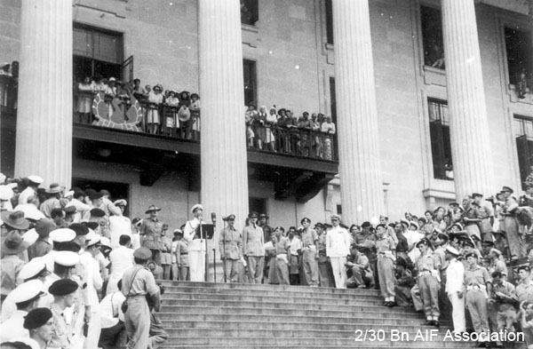 Japanese surrender, Singapore, 1945
022 - View of broadcast - Admiral Mountbatten giving a public address on the steps of the Singapore Municipal Buildings during the Japanese surrender ceremony. To the left of Mountbatten is Lieutenant General Slim and to the right are Lieut. General Wheeler and Air Chief Marshal Sir Keith Park. 
Keywords: Surrender