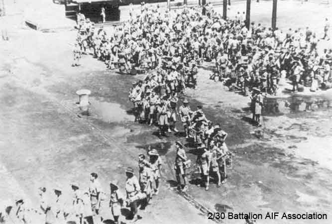 Waiting to board at Singapore
The Battalion embarking at Singapore for return to Australia on the Esperance Bay. "Black Jack" is looking on in the right centre of the photograph.

